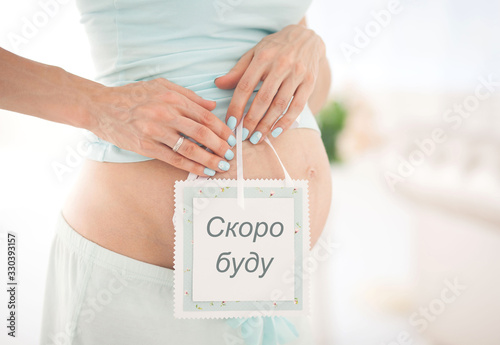 pregnant woman holds a tablet with the words I will be soon in Russian