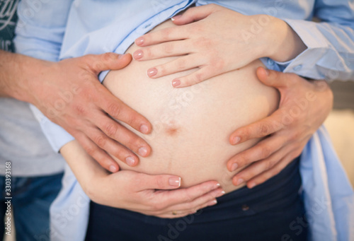 hands of the whole family on the belly of a pregnant mother