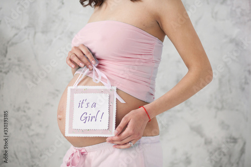 belly of a pregnant woman holding a tablet in her hands is a girl