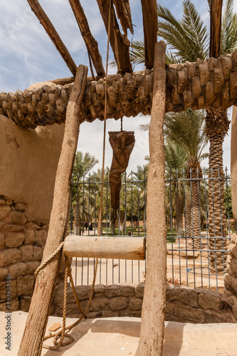Foto A palm tree trunk reel and leather bucket of the traditional Arab water well in