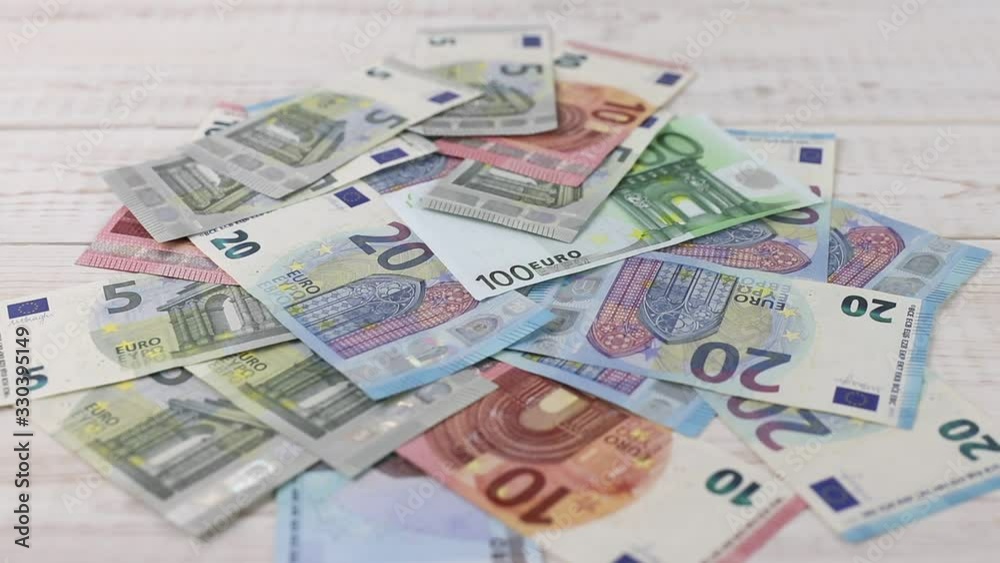 Blurred background with euro banknotes on white wooden table and hand of investor putting piggy bank. Concept of finance and growing saving wealth Blurred background with euro banknotes on white wooden table and hand of investor putting piggy bank. Concept of finance and growing saving wealth