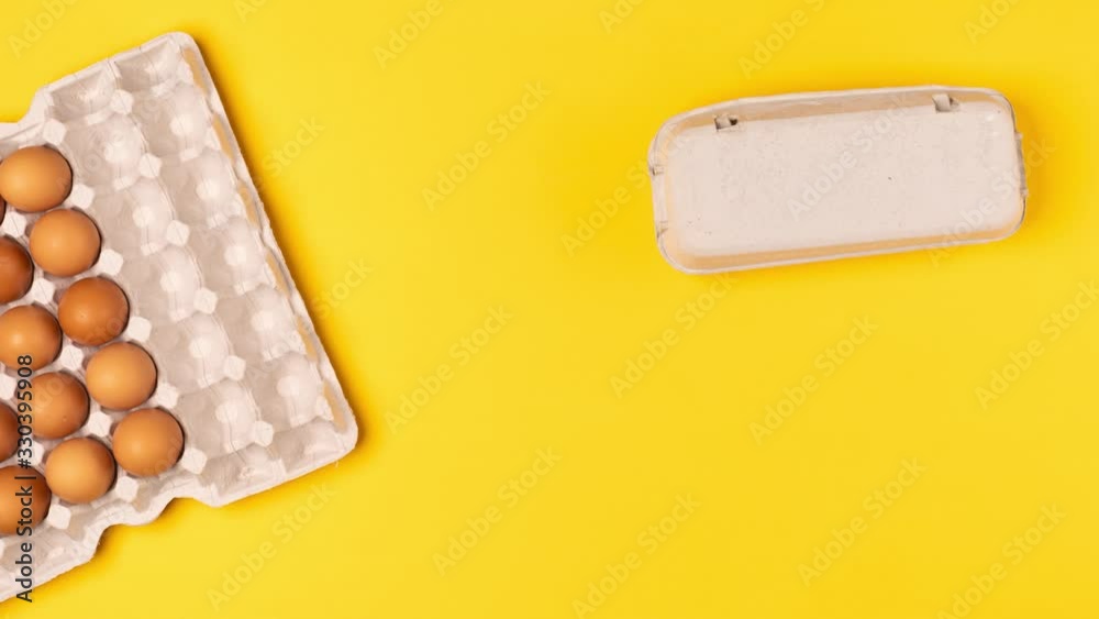 Brown eggs in a cardboard box disappear and appear in another box and move on a yellow background. Top view, stop motion animation Brown eggs in a cardboard box disappear and appear in another box and move on a yellow background. Top view, stop motion animation