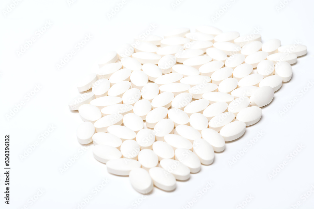A large number of tablets of white oval-shaped tablets on a white background. View from above. Isolated A large number of tablets of white oval-shaped tablets on a white background. View from above. Isolated
