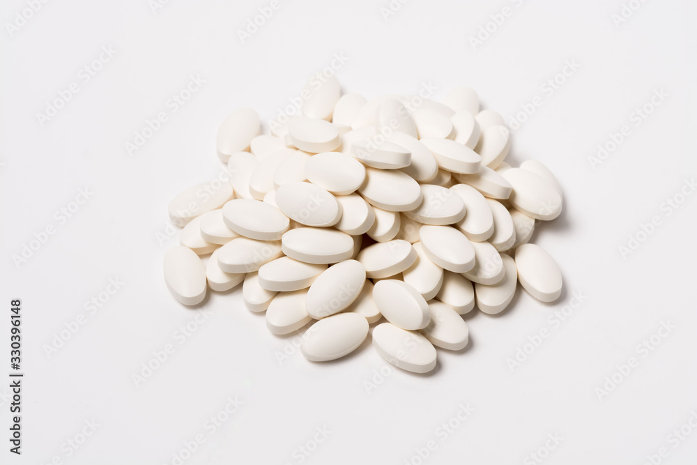 A pile of white oval-shaped tablets on a white background. View from the side A pile of white oval-shaped tablets on a white background. View from the side