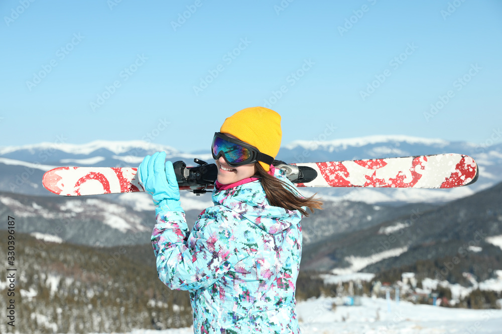 Young woman with ski equipment in mountains. Winter vacation
