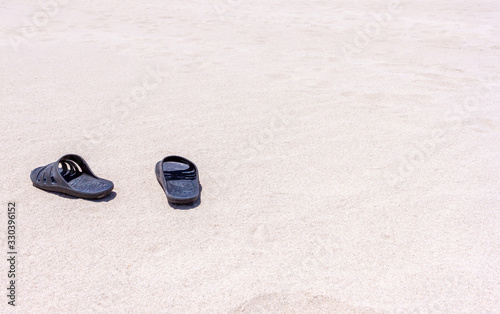 Black rubber slippers on the sand near the sea in africa desert