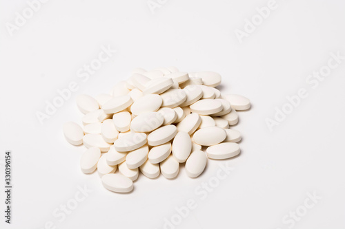 A pile of white oval-shaped tablets on a white background. View from the side. Isolated