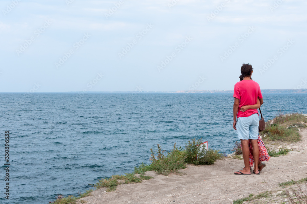 - Loving couple on the seashore looks into the distance.