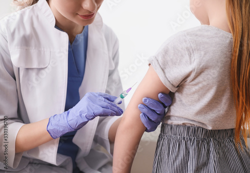 Little girl receiving chickenpox vaccination in clinic, closeup. Varicella virus prevention photo