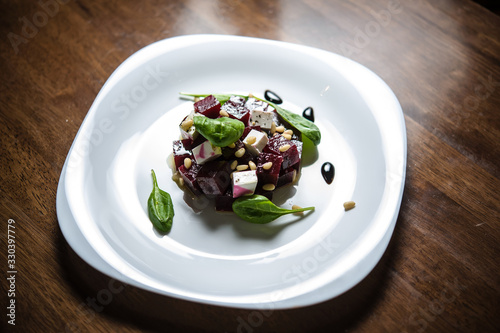Salad with beetroot and feta cheese, spinach leaves, toasted pine nuts in white ceramic bowl. For food blogs, restaurant menus, and content related to vegetarian or Mediterranean cuisine