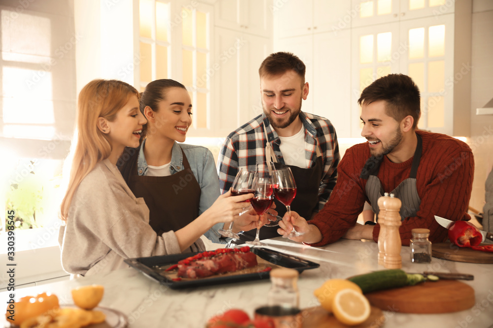 Happy people drinking wine while cooking food in kitchen