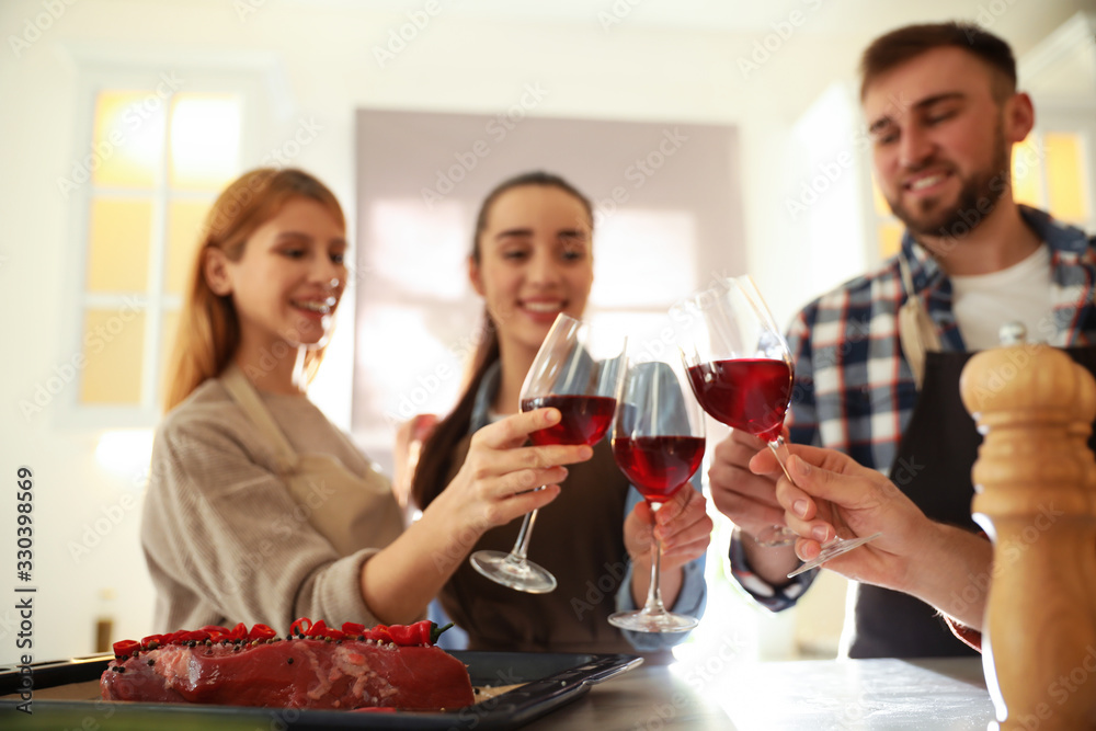 Happy people drinking wine while cooking food in kitchen Happy people drinking wine while cooking food in kitchen