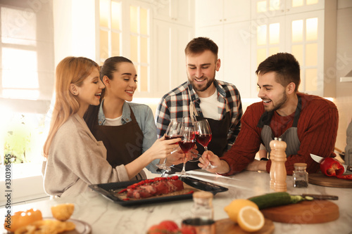 Happy people drinking wine while cooking food in kitchen