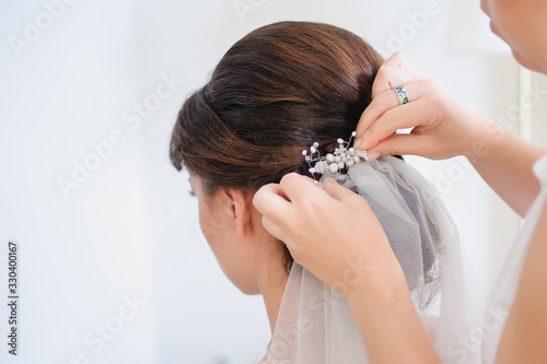 Hairstyle of the bride. Preparations for the wedding ceremony, makeup, beauty. Stylist is putting on diadem. Hair stylist or florist makes the bride a wedding hairstyle