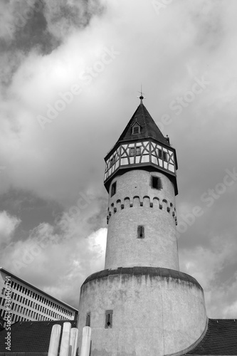 Wolken über dem alten Turm der Bockenheimer Warte mit Fachwerk bei Sonnenschein im Stadtteil Bockenheim in Frankfurt am Main in Hessen in neorealistischem Schwarzweiß photo