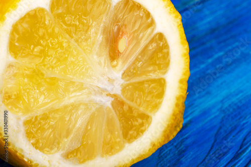 Fresh sliced juicy yellow citrus fruit lemon. On wooden blue background. photo