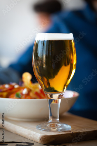 Glass of beer and chips on wooden table