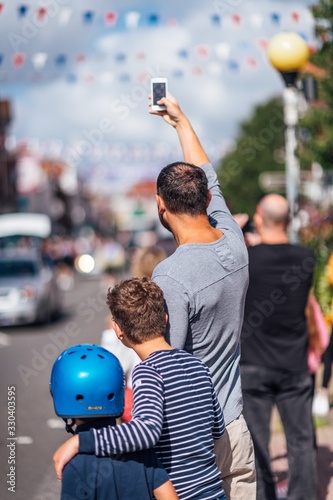 Vertical shot of a group of people taking photos of the parade during daytime