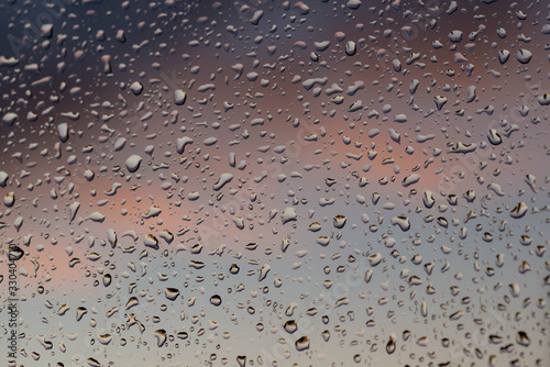Okienna szyba pokryta kroplami deszczu.