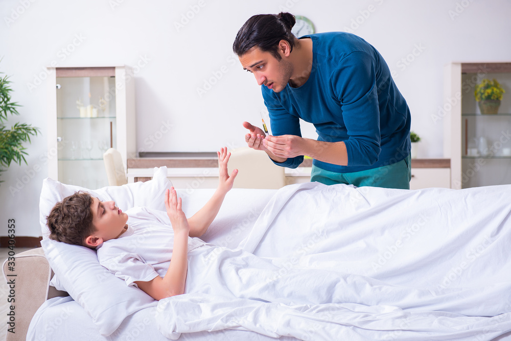 Fototapeta premium Young father caring for sick son