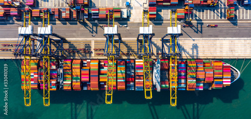 Aerial top view over international cargo ship at industrial import-export port prepare to load containers with big container loader ship vessel. Oversea international Business.