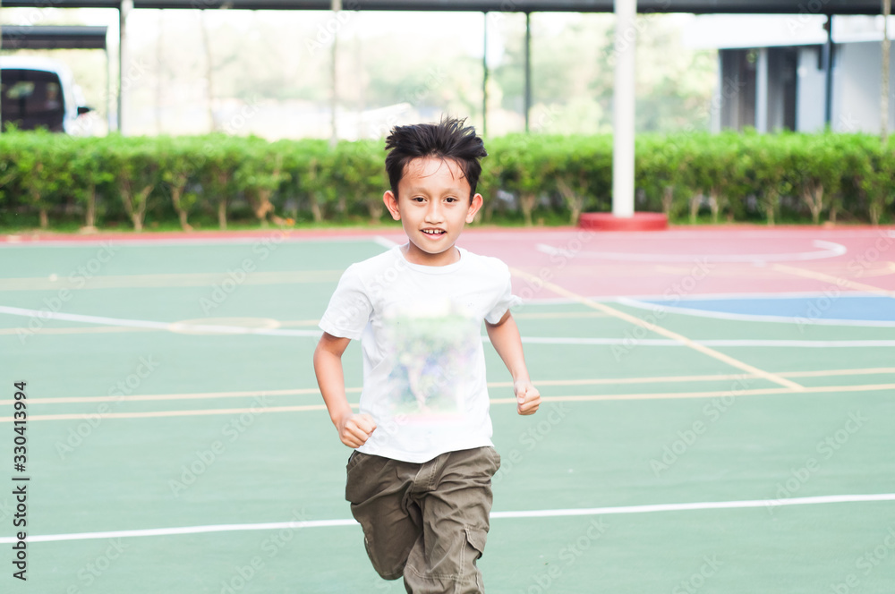 Boy running at the basketball court, being active and cheerful.