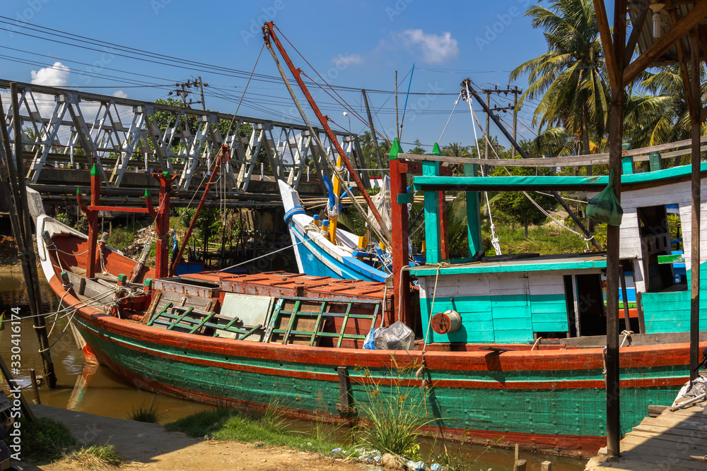 Old wooden fishing boats stand in a small port of southeast asia