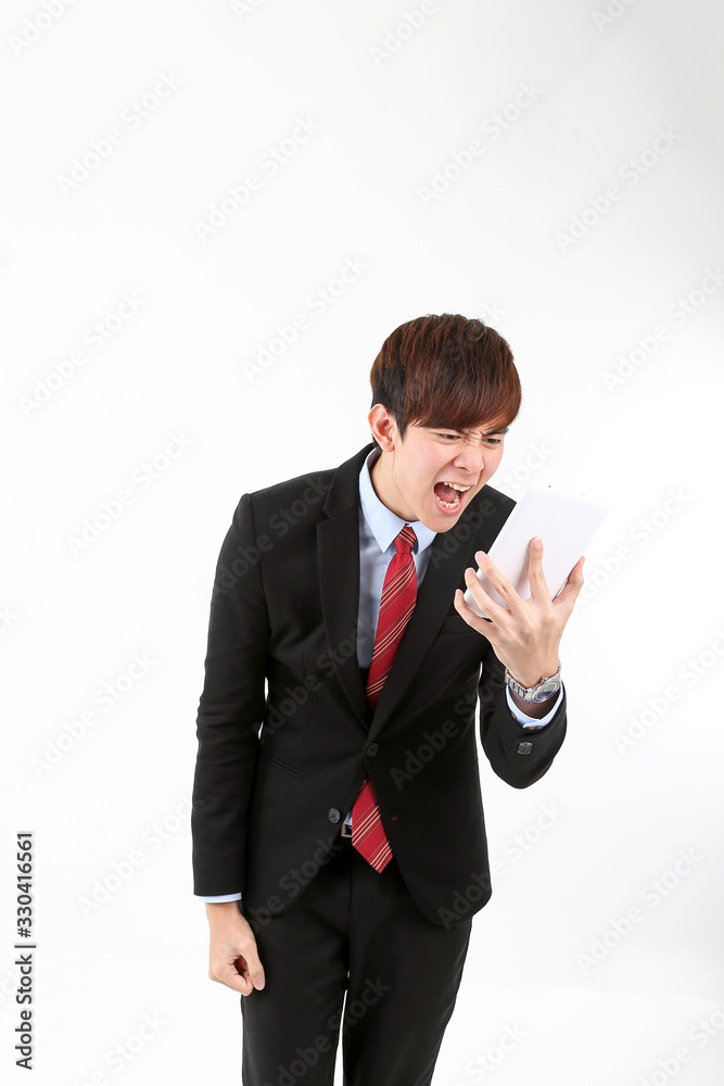 Young smart handsome Asian man business office wearing suit tie on white background looking at smartphone massage angry exited shouting Young smart handsome Asian man business office wearing suit tie on white background looking at smartphone massage angry exited shouting