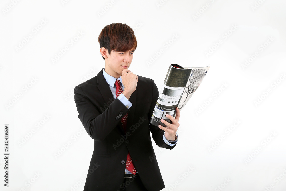 Young smart handsome Asian man business office wearing suit tie on white background reading book magazine hand on chin concentrate Young smart handsome Asian man business office wearing suit tie on white background reading book magazine hand on chin concentrate