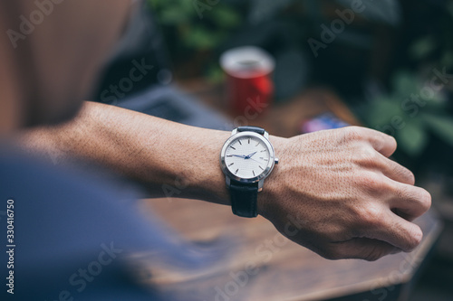 looking at luxury watch on hand check the time at workplace.concept for managing time organization working,punctuality,appointment.fashionable wearing stylish photo