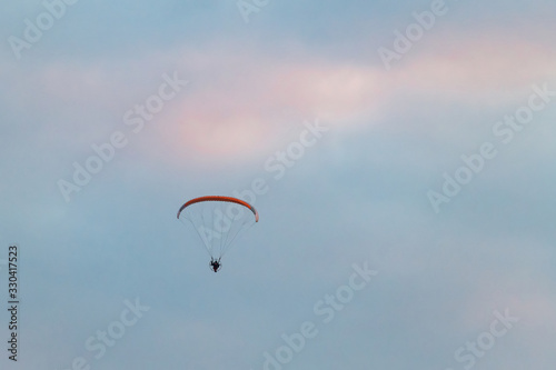 Powered paragliding, man flying high in a sky with parachute and engine on his back