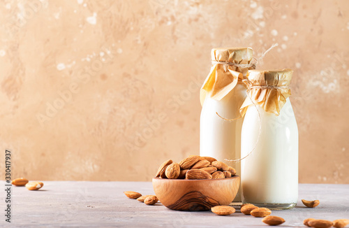 Cuadro en lienzo Almond milk with almond on brown table