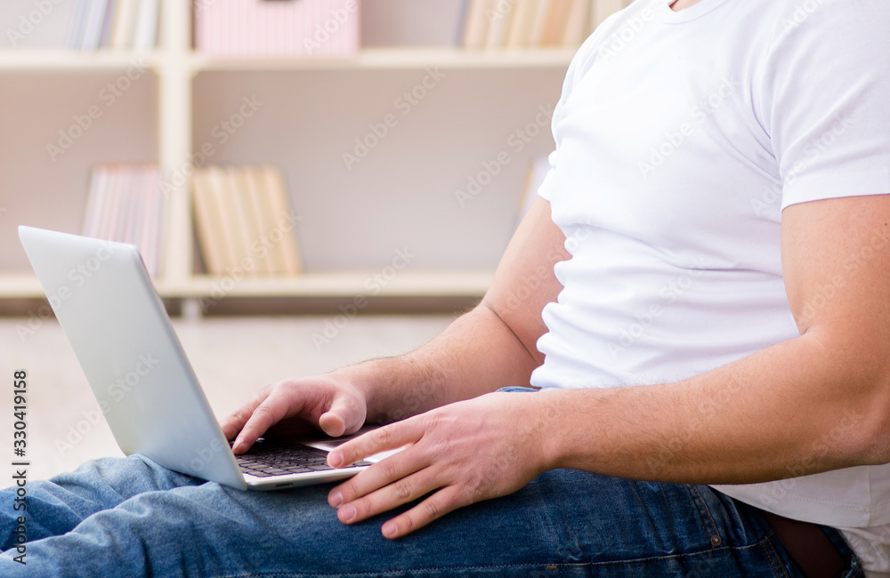 Fototapeta premium Man working on laptop at home on carpet floor