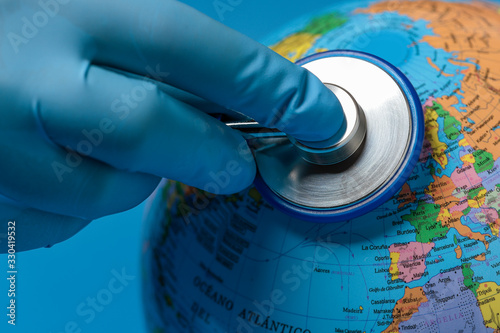 Obraz na plátne hand with blue glove auscultating the terrestrial globe