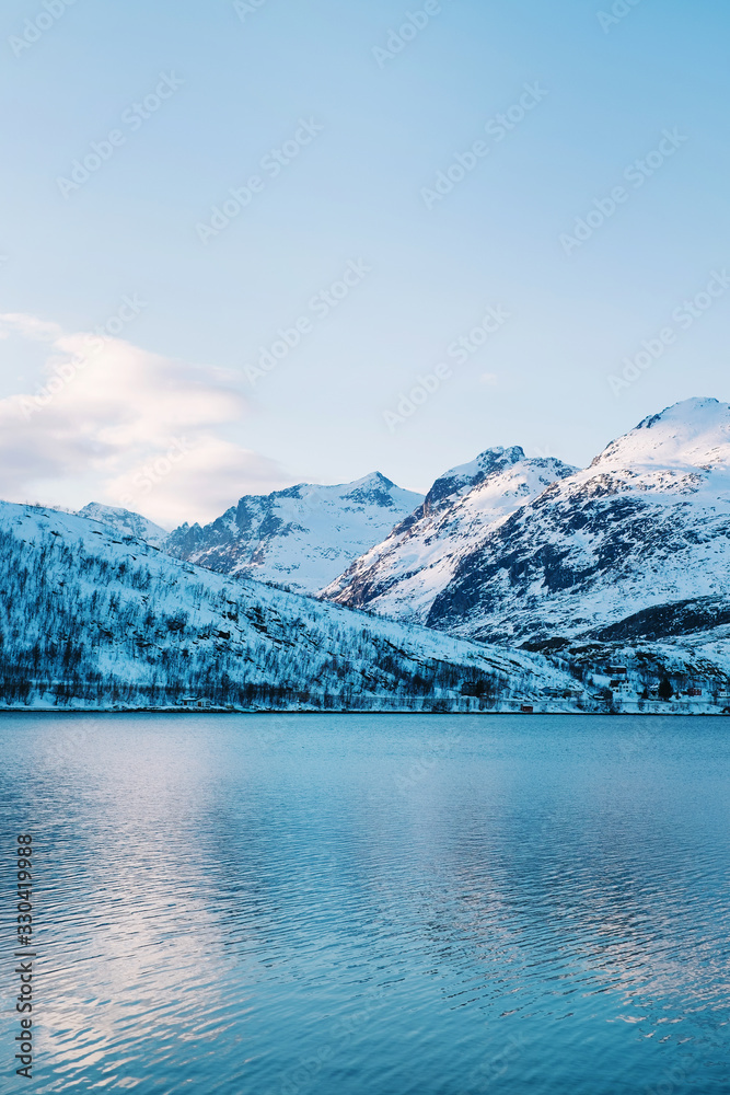Snowy blue winter fjord and mountain view of Kaldfjord and Arctic ocean on Kvaloya island in Troms, Northern Norway, in the Arctic Circle