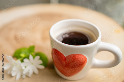 Cup coffee, jasmine flower on wooden table.