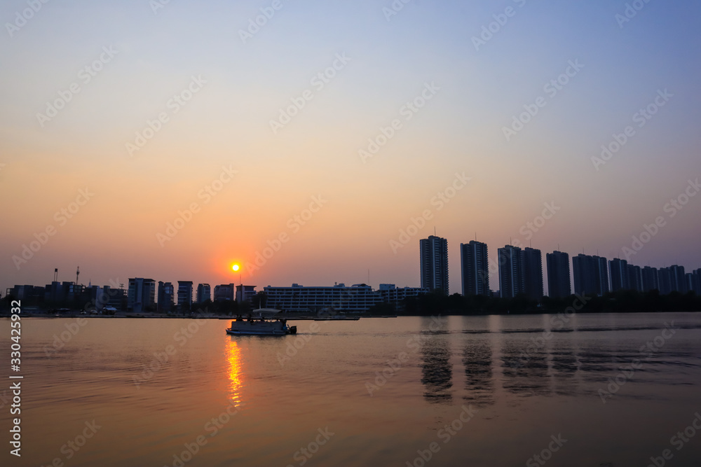 Fototapeta premium CItyscape modern apartment building near a lake under sunset twilight with cloud sky background with water reflections for background.