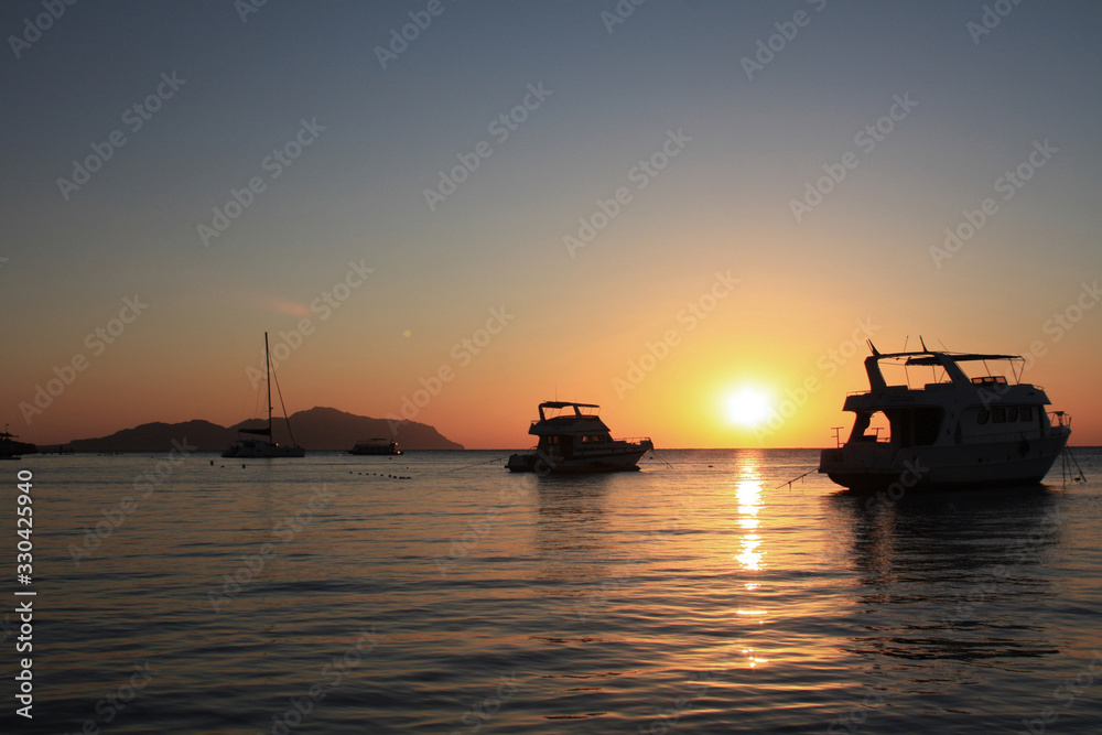 Silhouette yacht boat against the background of the sky of a sunny sunset. Silhouettes of ships on the background of the ocean and the sun. beautiful seascape for travel companies,boat trips, romance.