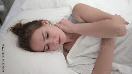 Sleeping Young Woman having Neck Pain in Bed