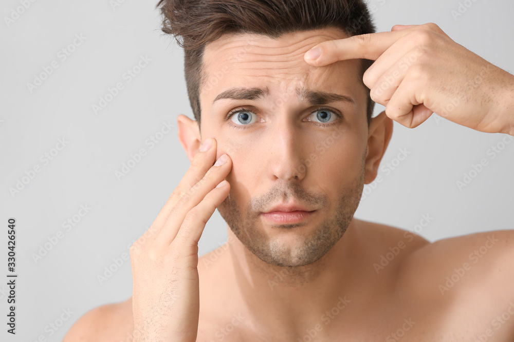 Young man worried about his appearance on light background. Plastic surgery concept Young man worried about his appearance on light background. Plastic surgery concept