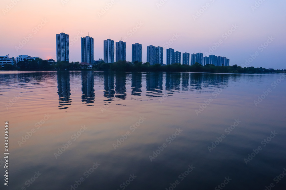 CItyscape modern apartment building near a lake under sunset twilight with cloud sky background with water reflections for background.