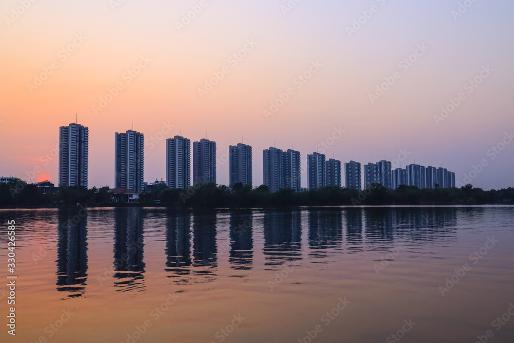 CItyscape modern apartment building near a lake under sunset twilight with cloud sky background with water reflections for background. CItyscape modern apartment building near a lake under sunset twilight with cloud sky background with water reflections for background.