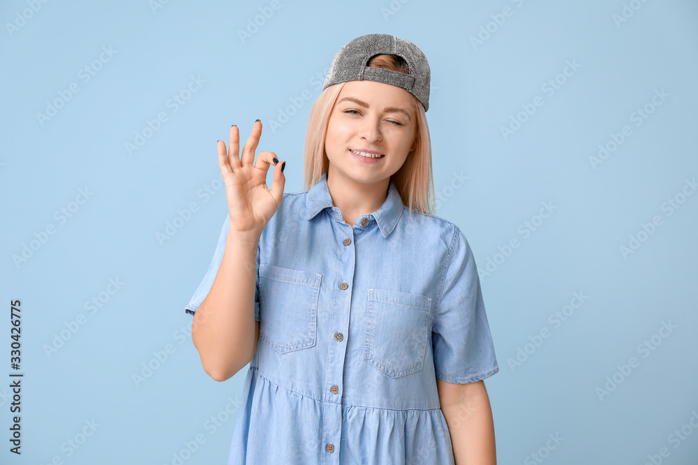 Cool young woman showing OK on color background Cool young woman showing OK on color background