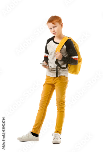 Cute little boy with mobile phone and backpack on white background