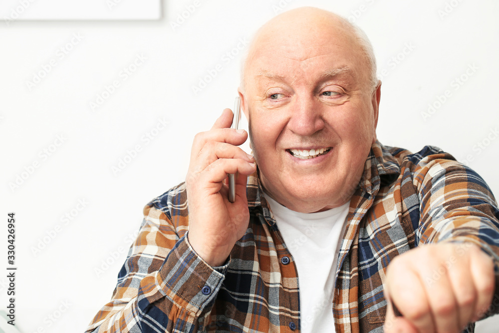 Portrait of elderly man talking by phone at home Portrait of elderly man talking by phone at home