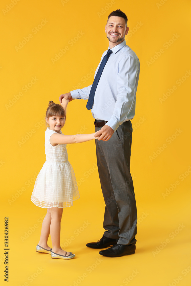 Father and his little daughter dancing against color background Father and his little daughter dancing against color background