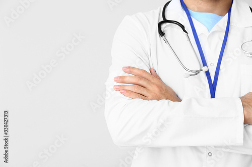Young male doctor on light background, closeup
