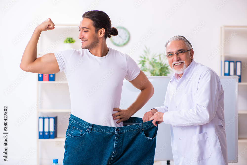 Obraz premium Doctor dietician and happy patient wearing large trousers