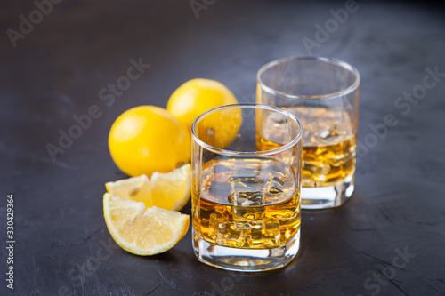 whisky with ice and a lemon in a glass against a dark background, selective focus, copy space