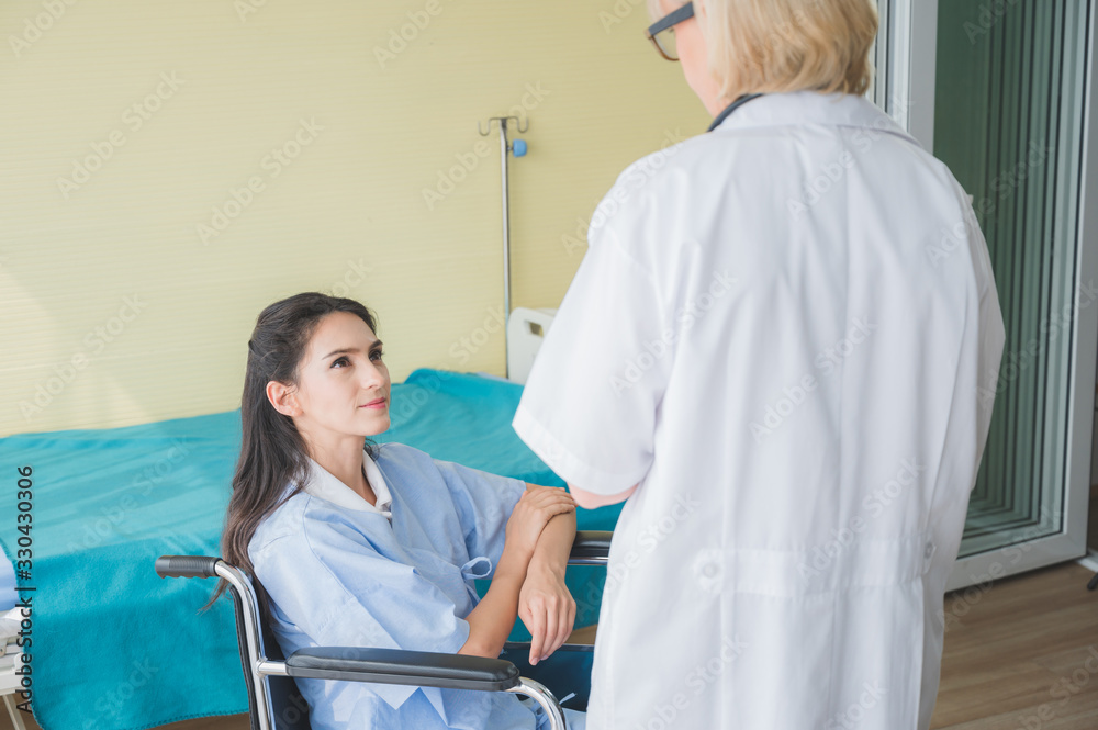 The doctor takes care of the female patient sitting on the wheelchair The doctor takes care of the female patient sitting on the wheelchair